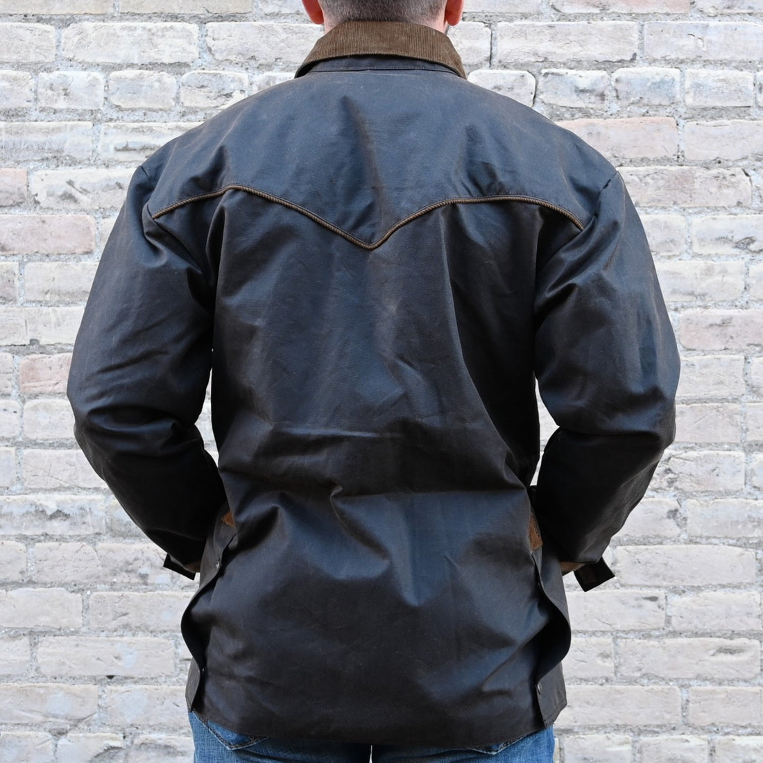 View of Oak waxed canvas RangeWax Drifter coat with leather collar, corduroy trim, pockets, and storm flap