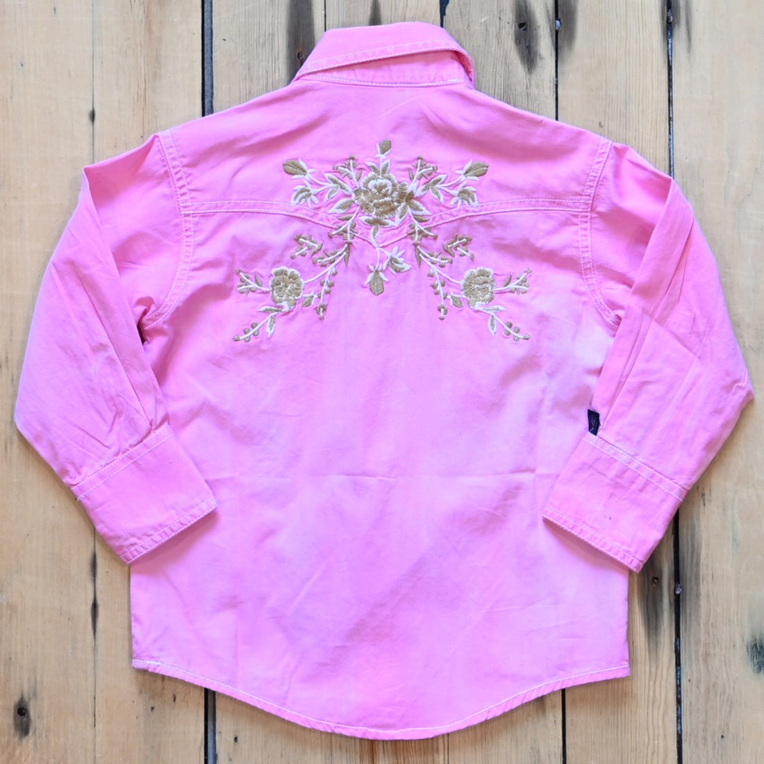 View of Rockmount kids stonewash pink western shirt with floral embroidery and western piping