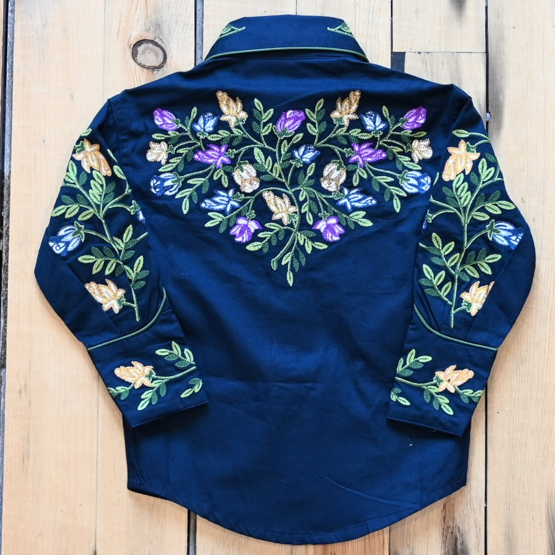 View of Rockmount kids navy shirt with embroidered crochet floral pattern, piping, and western detailing