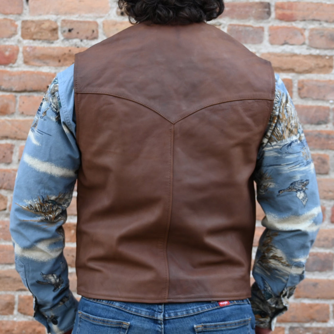 View of Schaefer whiskey-colored leather vest with Western yoke design, lapel front, and dual pockets