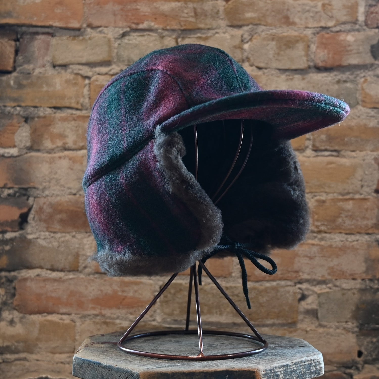 View of Filson Double Mackinaw Cap in Forest Green/Acorn and Burgundy/Dark Olive Plaid featuring shearling-lined earflaps and a 3" bill