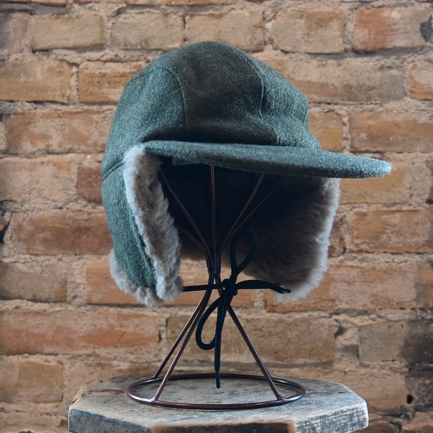 View of Filson Double Mackinaw Cap in Forest Green/Acorn and Burgundy/Dark Olive Plaid featuring shearling-lined earflaps and a 3" bill