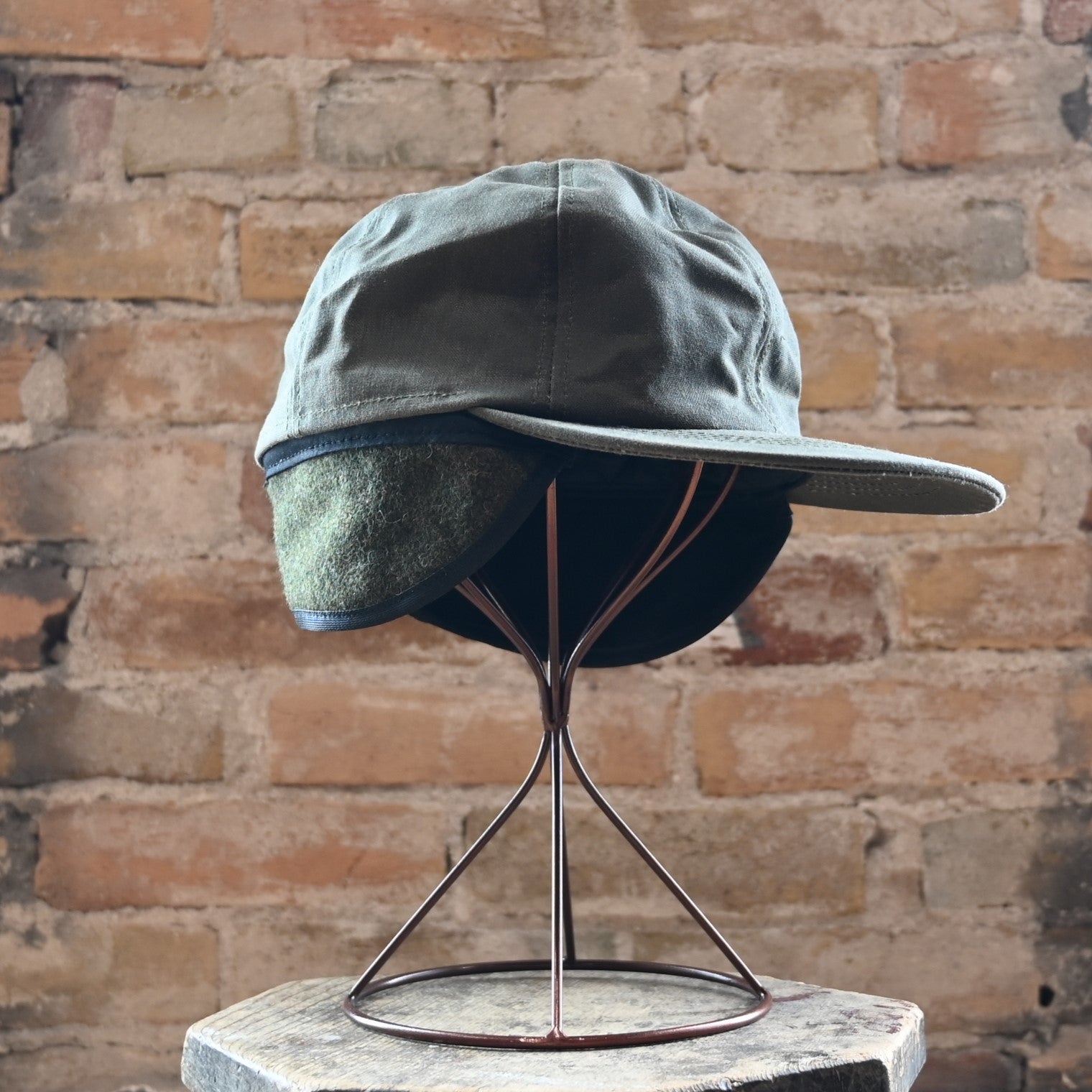 View of Filson Insulated Tin Cloth Cap in Otter Green featuring wool ear/neck flap and 3" pre-curved bill