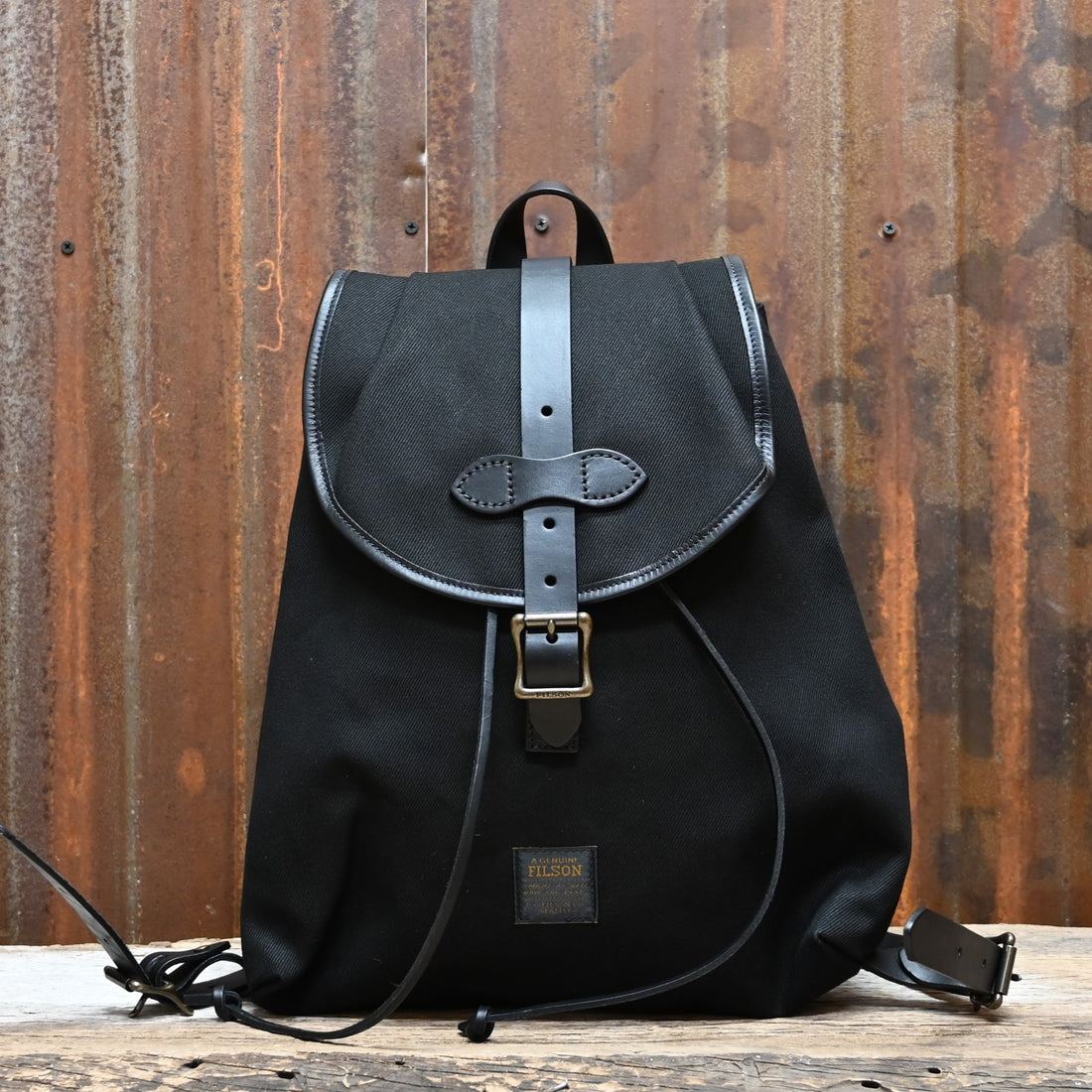 View of Filson Rugged Twill Drawstring Backpack in Black featuring leather straps and a rain flap