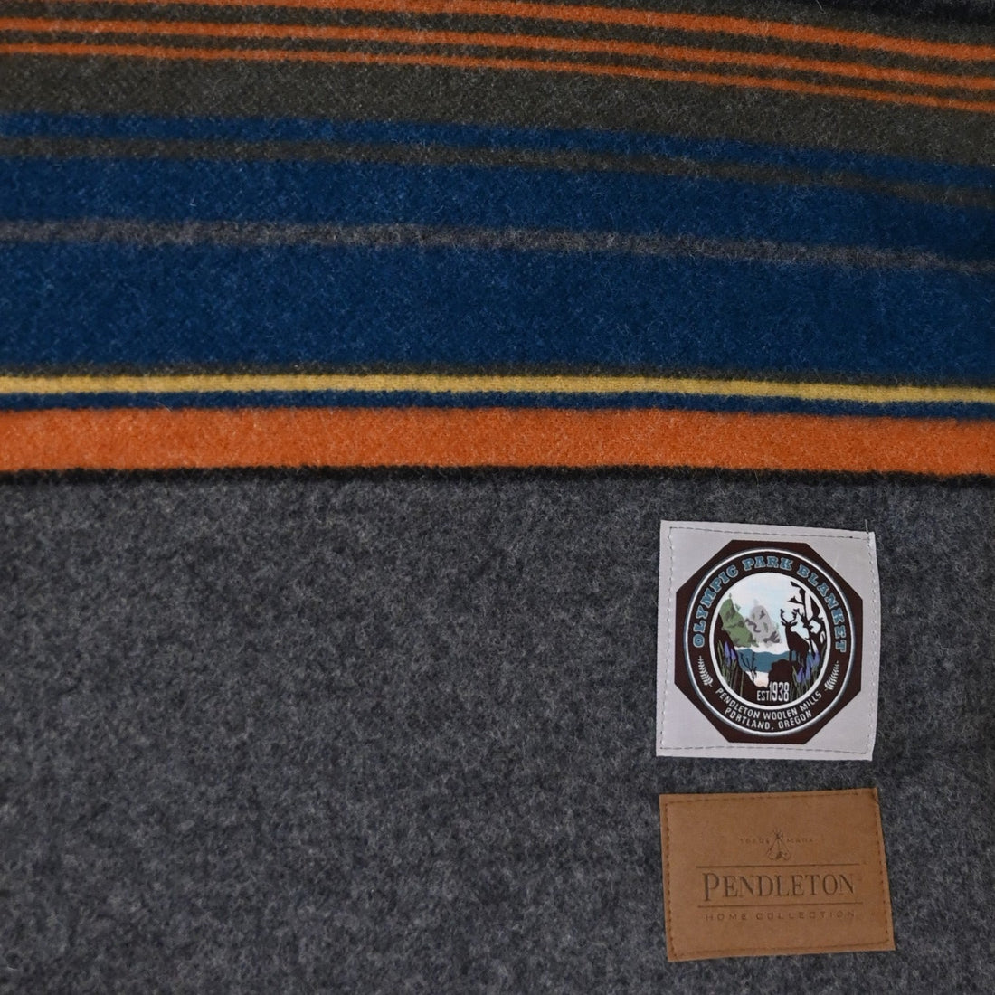 View of Pendleton Olympic Grey National Park blanket in twin size with blue, orange, yellow, black, and grey stripes