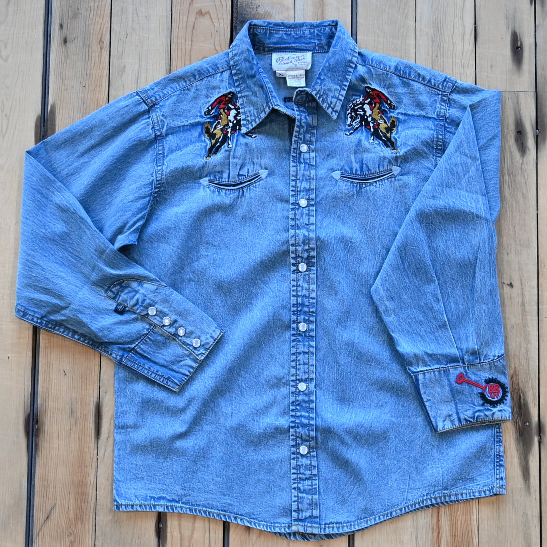 View of Rockmount kids denim shirt with bronc rider embroidery, piping, and snap western details