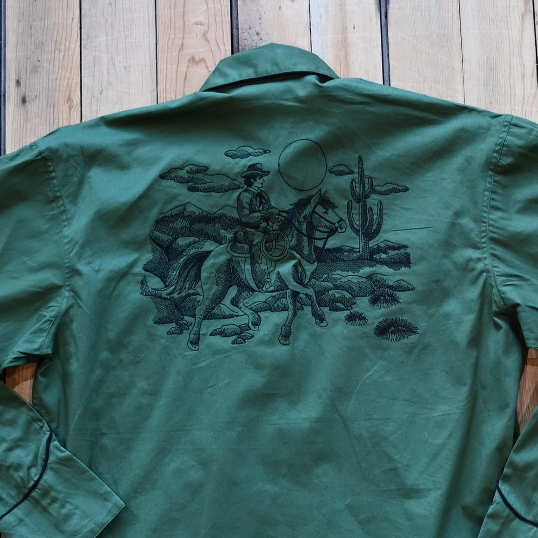 View of Green Western shirt with embroidered “man and rider” motif across yokes and cuffs