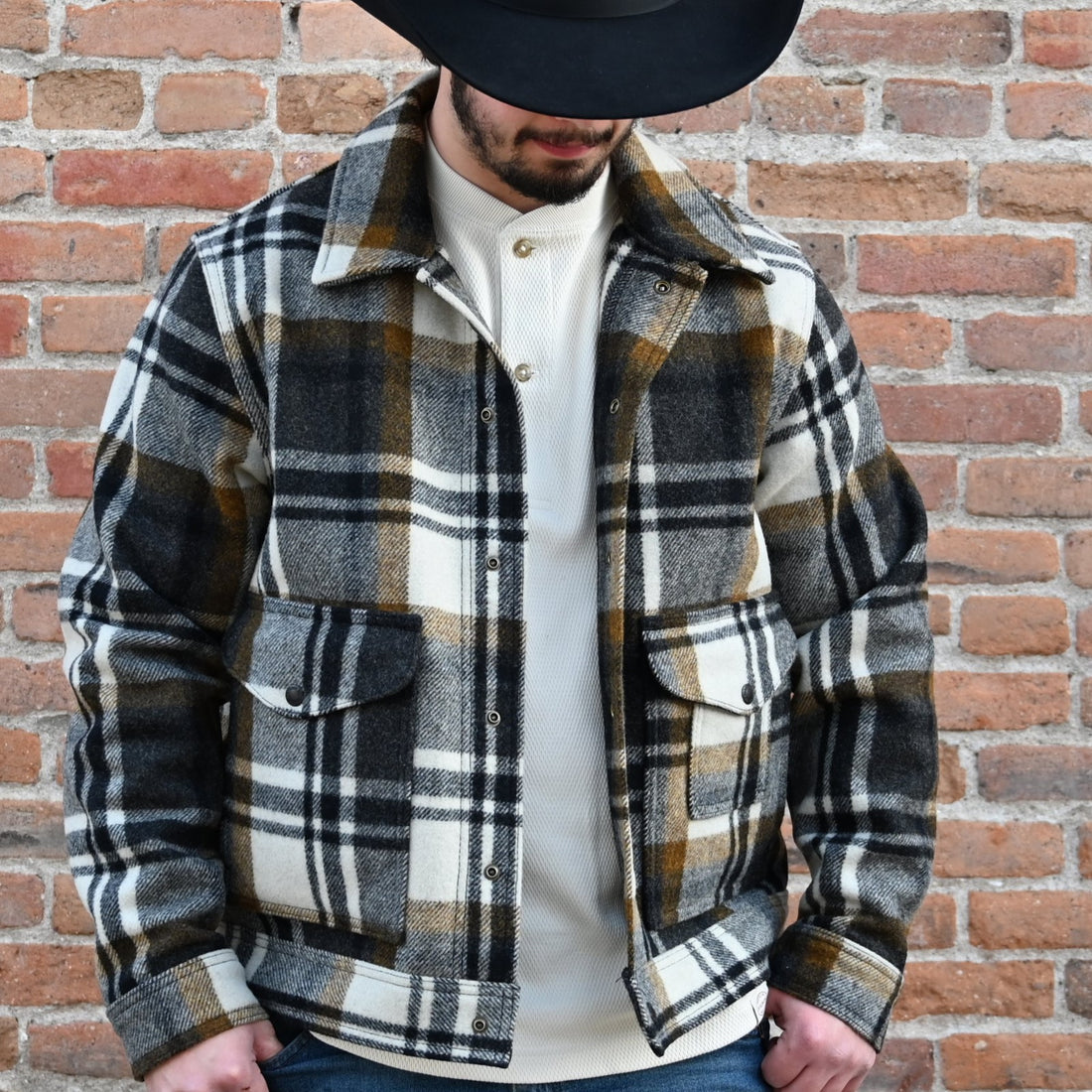 View of Filson Mackinaw Wool Work Jacket in Forest Green, showcasing snap-flap cargo and patch-hand pockets, and an internal stow pocket