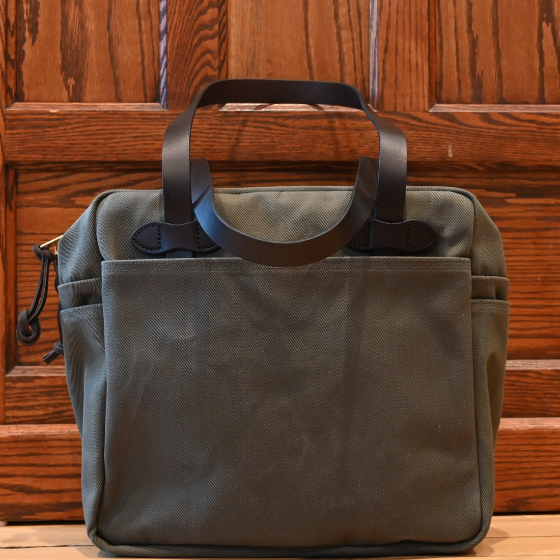 Filson rugged twill zip-top tote bag in otter green with leather handles and multiple exterior pockets