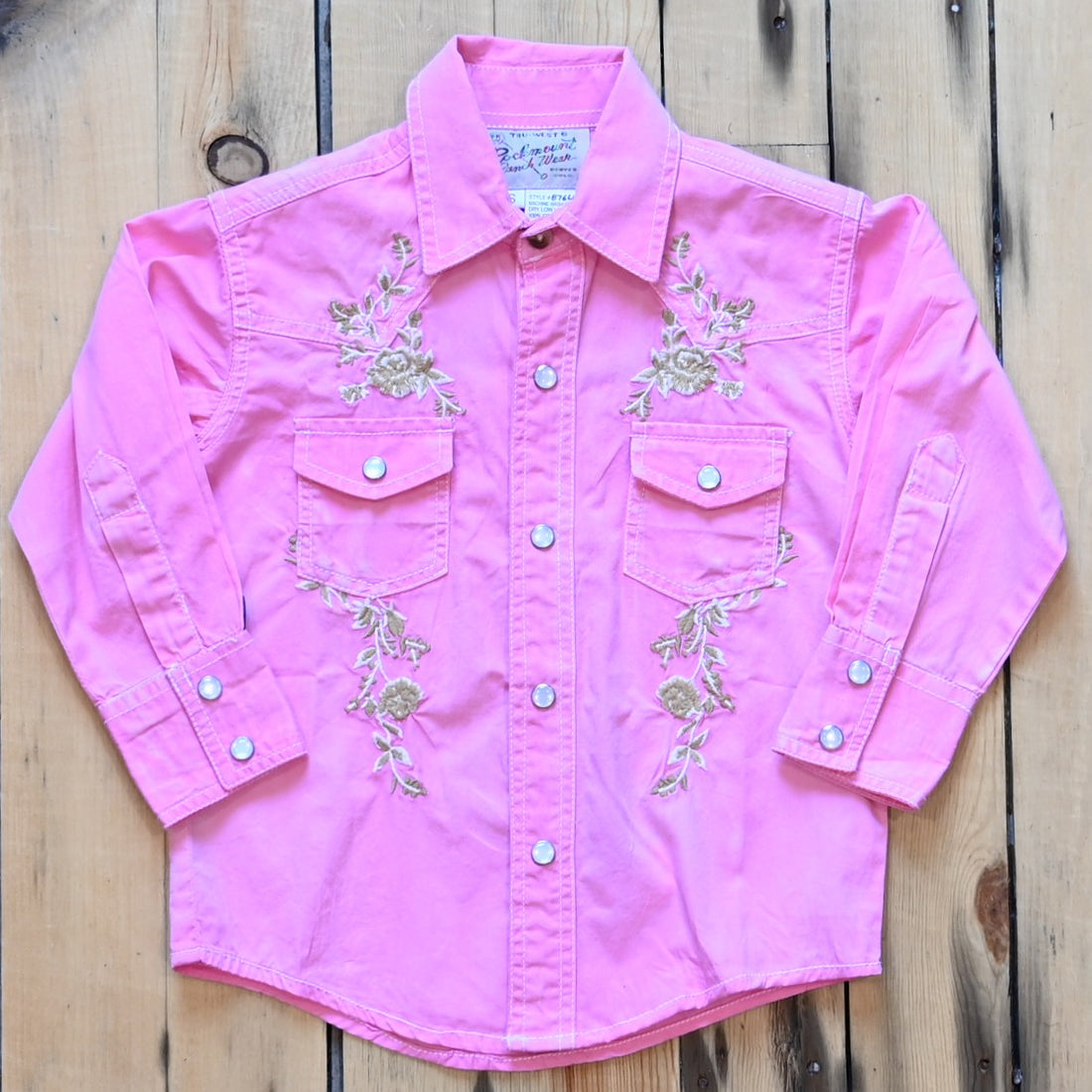View of Rockmount kids stonewash pink western shirt with floral embroidery and western piping