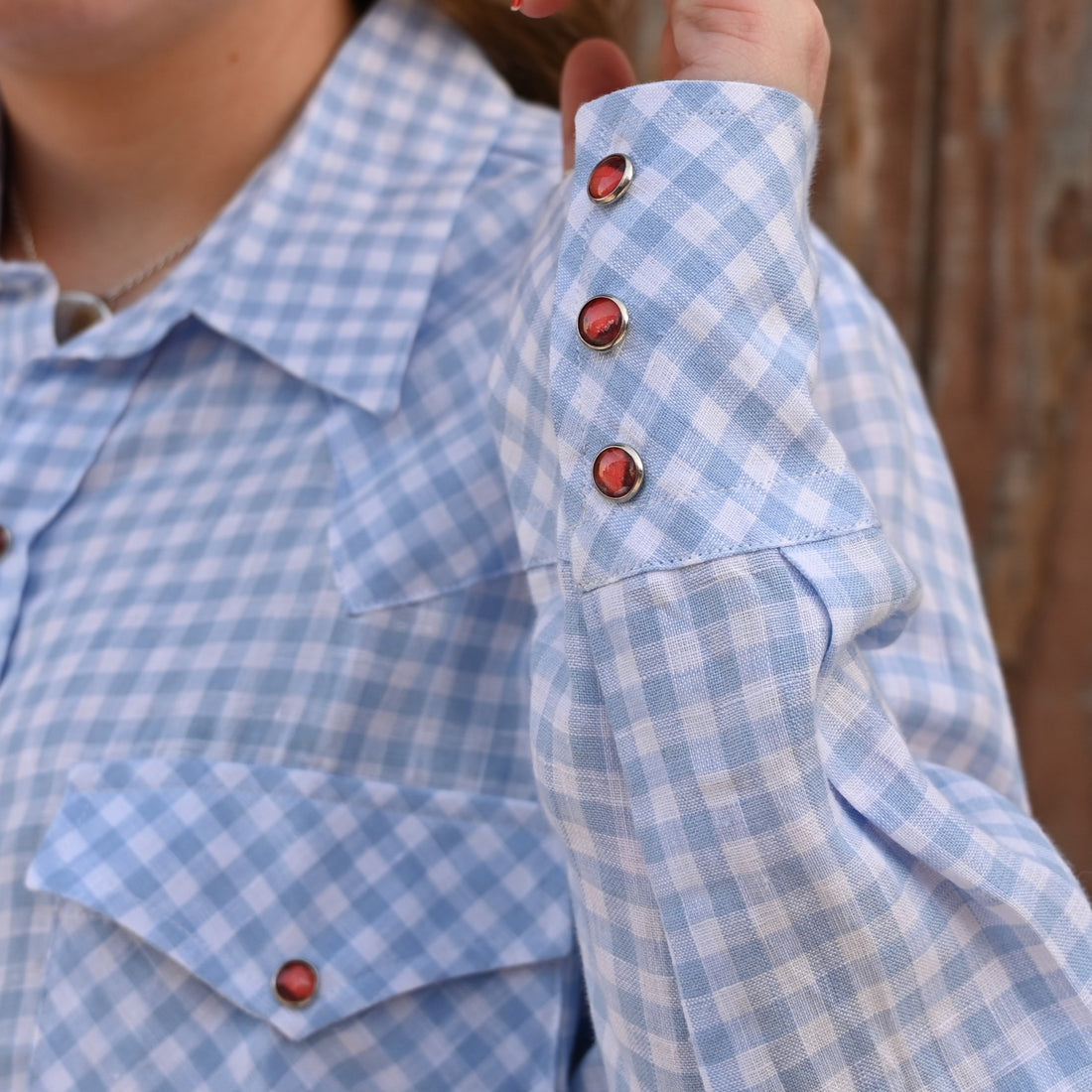 View of Blue Blanket ladies light blue linen Western shirt with orange pearl snaps and plaid pattern
