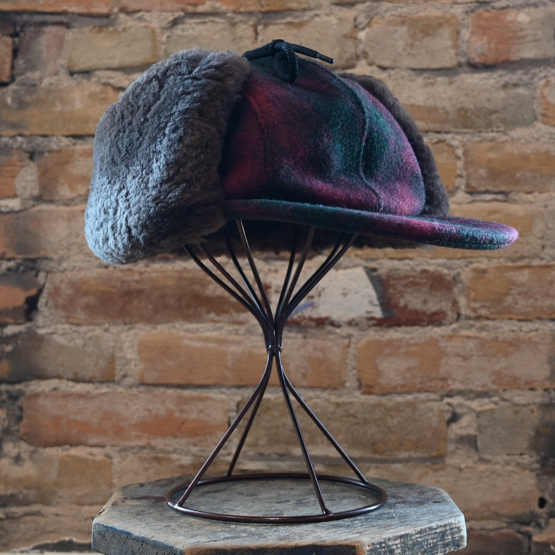 View of Filson Double Mackinaw Cap in Forest Green/Acorn and Burgundy/Dark Olive Plaid featuring shearling-lined earflaps and a 3" bill