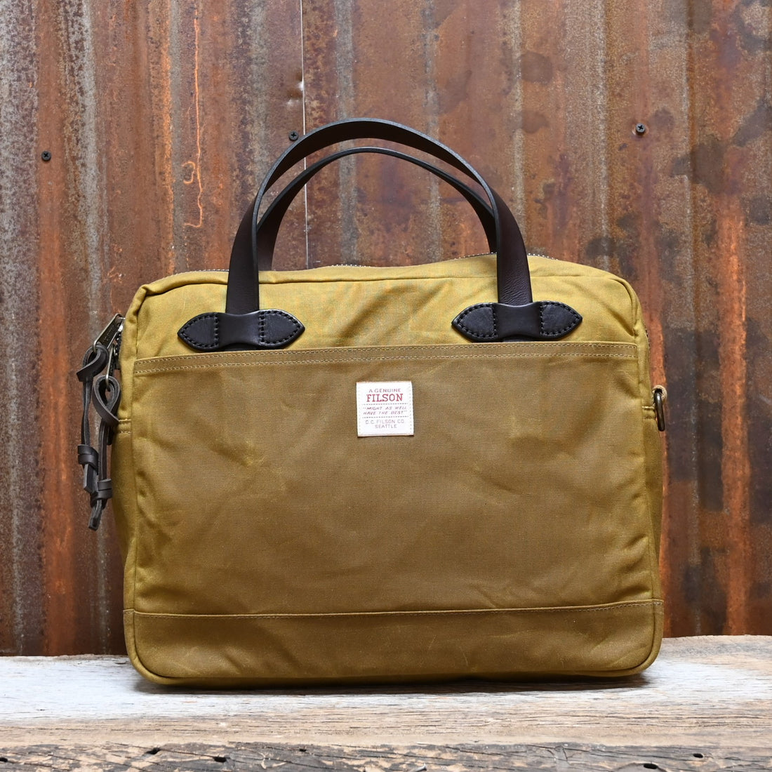 View of Filson Tin Cloth Compact Briefcase in Dark Tan, showcasing its durable waxed cotton exterior, leather handles, and padded laptop compartment