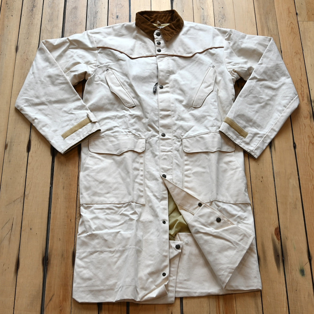 View of Natural canvas full-length duster with snap front, storm flap, and corduroy collar