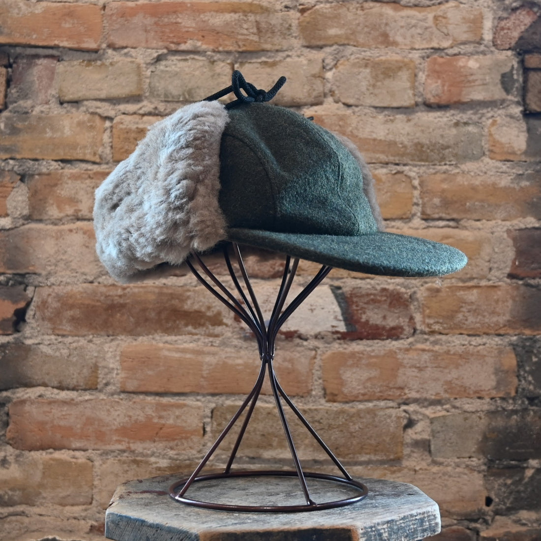 View of Filson Double Mackinaw Cap in Forest Green/Acorn and Burgundy/Dark Olive Plaid featuring shearling-lined earflaps and a 3" bill